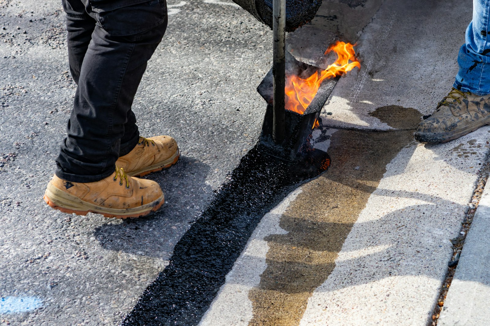 Crew applying hot asphalt to repair a commercial lot surface